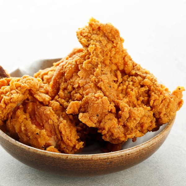 Close-up of crispy, golden-brown fried chicken pieces in a rustic bowl from Rapids Chicken.