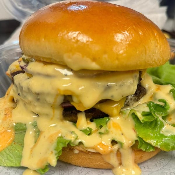 A Rapids Chicken double cheeseburger with melted cheese, lettuce, and special sauce on a brioche bun.